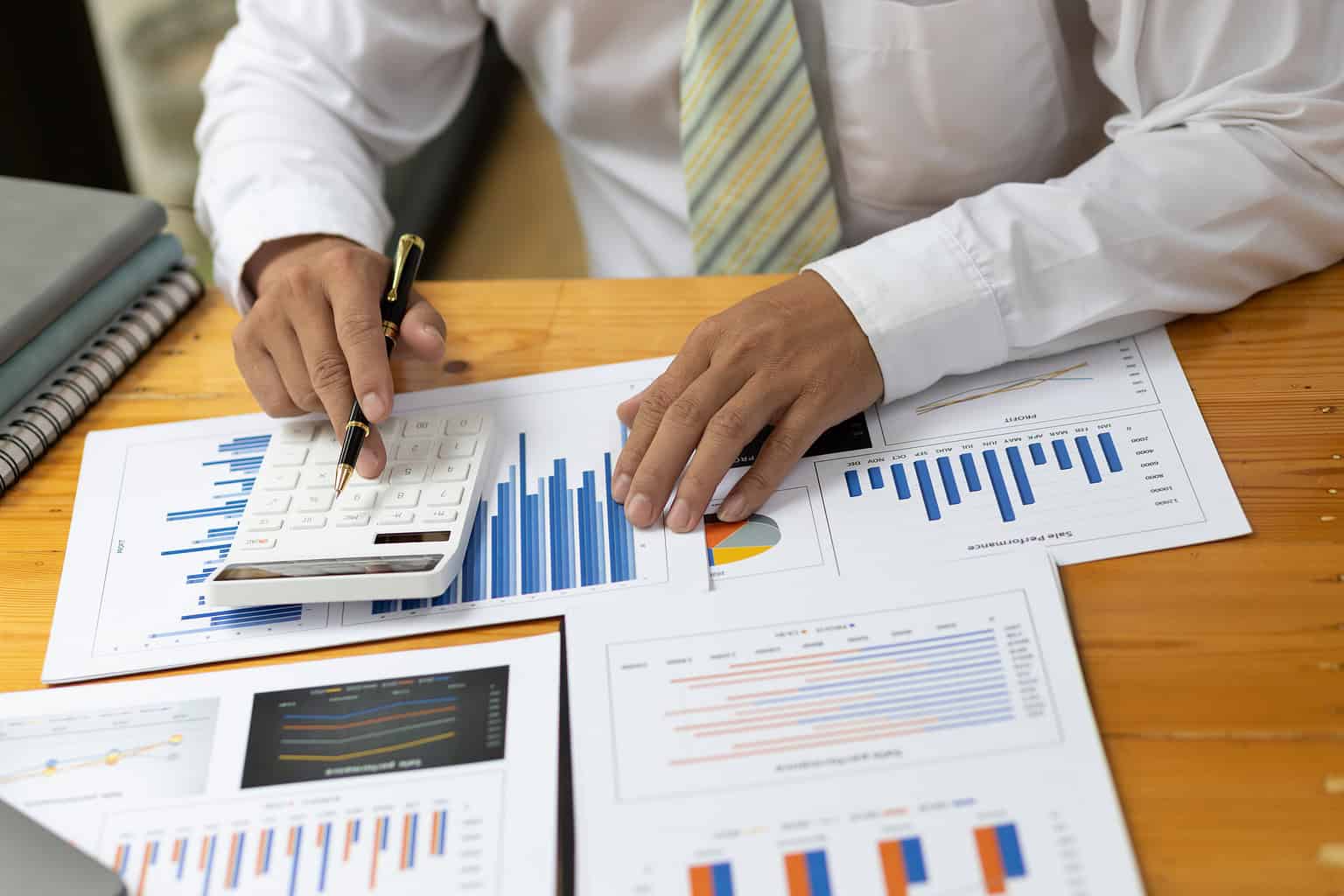 Businessman or accountant working Financial investment on calculator, calculate, analyze business and marketing growth on financial document data graph, Accounting, Economic, commercial concept.