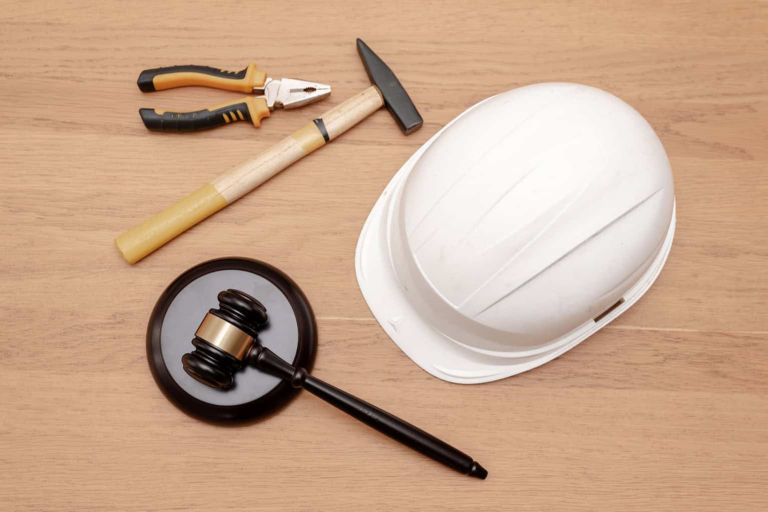 top view of Justice Gavel with white hard hat and industrial tools on wooden background, Construction law concept